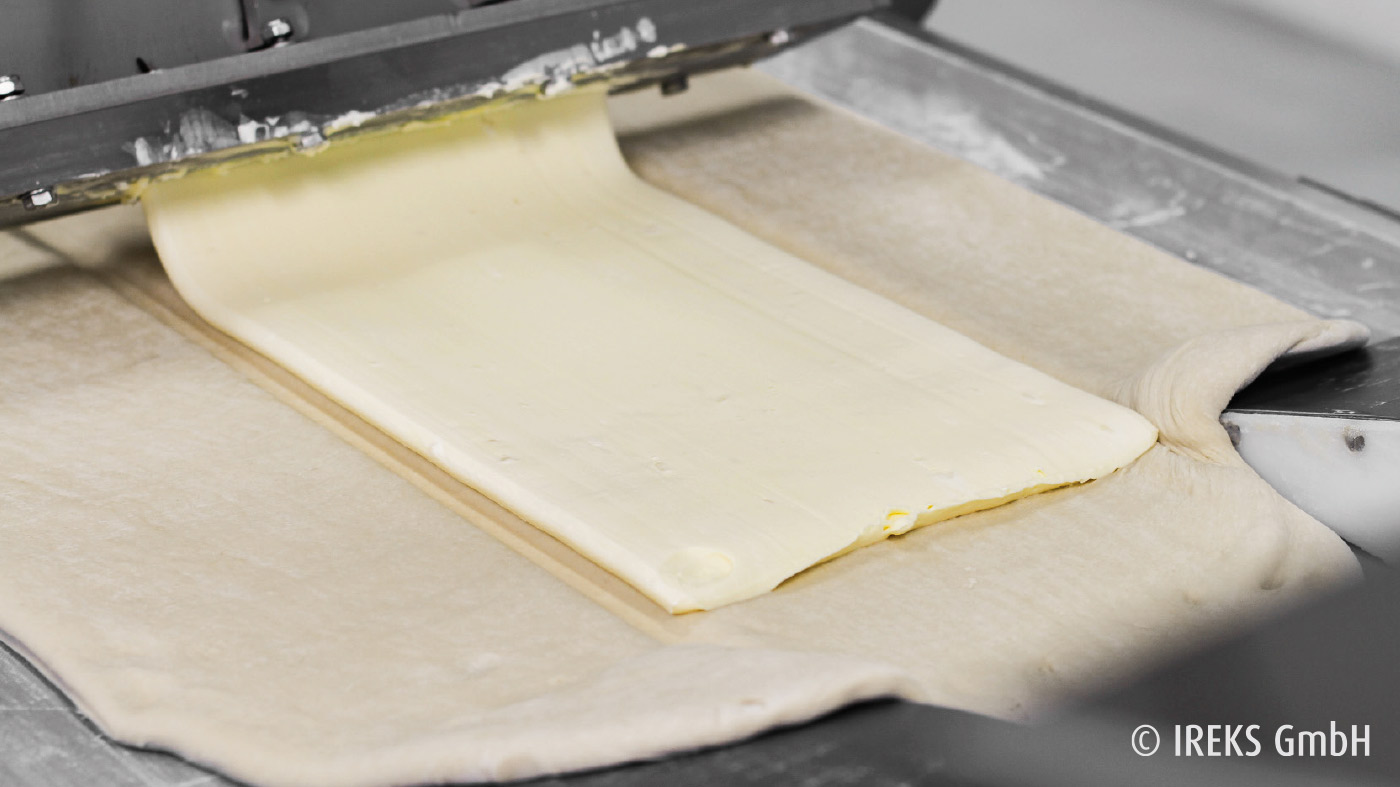 Fettpumpe bringt Butter auf das Teigband auf 