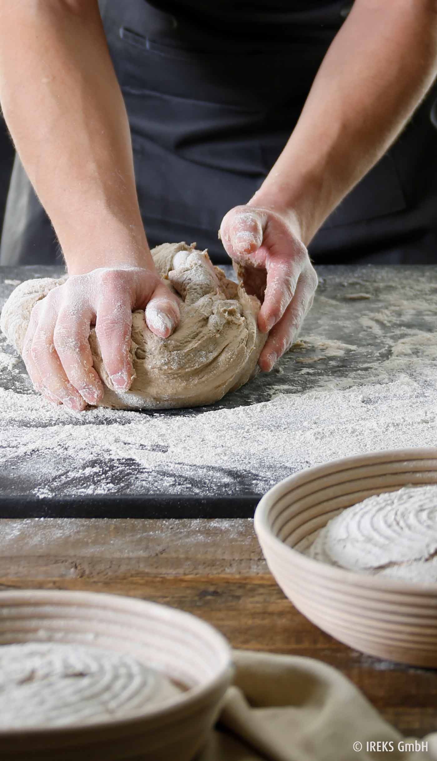 Bäcker knetet Teig auf Steinplatte, Mehl, Holzschüssel